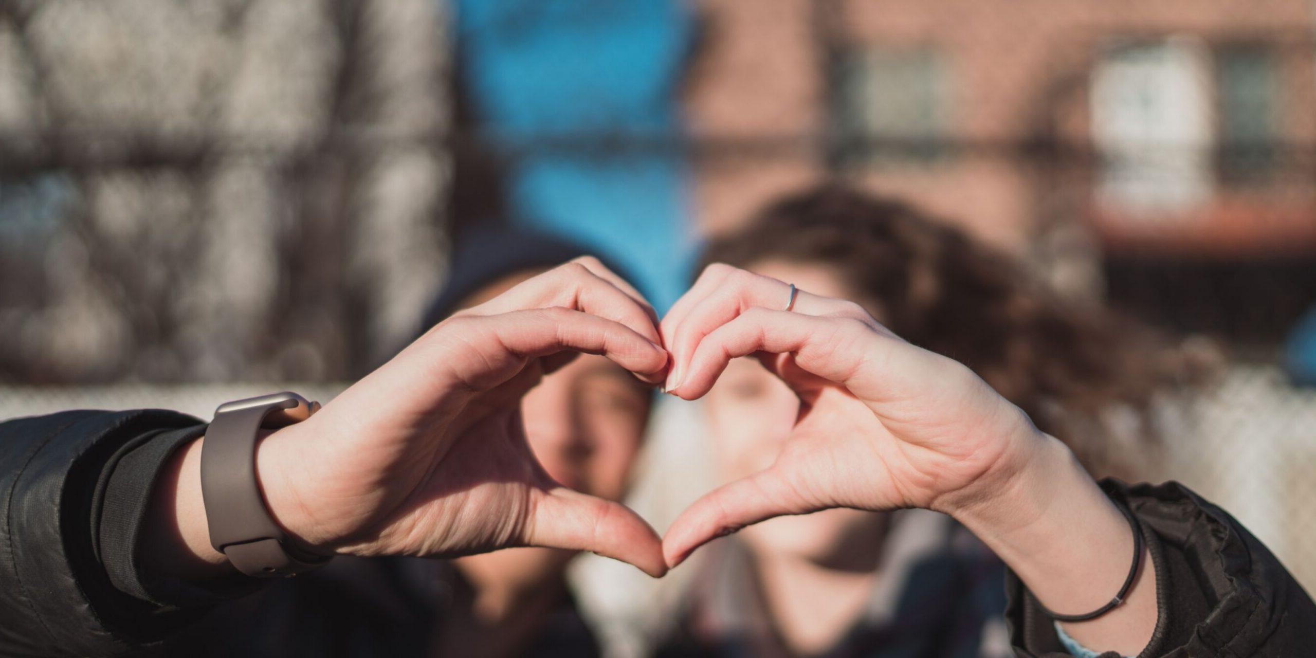 two people making the heart sign with hands